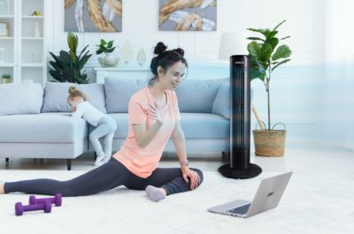 Fitness woman exercising on the floor at home and watching fitness videos in a laptop. Young female trainer doing online fitness training for her clients.