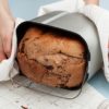 Woman’s hands taking off bread from the breadmaker