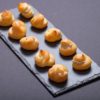 Set of small profiteroles on a black slate plate. Selective focu