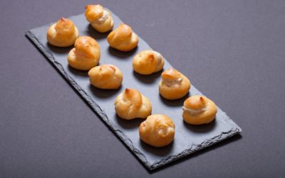 Set of small profiteroles on a black slate plate. Selective focu